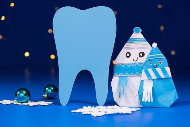 Weihnachtszahnheilkunde große Zahnschneemänner und -bälle auf einem blauen Hintergrund