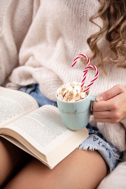 Weihnachtszauberszene, gemütliche Atmosphäre. Frau, die Tasse Getränk mit Marshmallows hält.