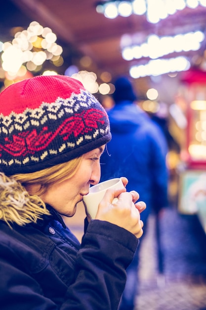Weihnachtszeit auf dem Weihnachtsmarkt genießen Junges Mädchen trinkt Glühwein