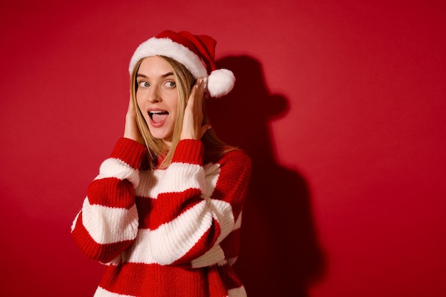 Weihnachtszeit. Hübsches junges Mädchen in einer Weihnachtsmütze und einem gestreiften Pullover