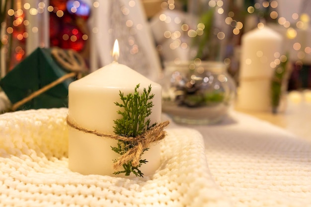 Weihnachtszeit weiße Kerze verzierte Geschenke grüne Tannenzweige und goldene funkelnde Hintergrundlichter