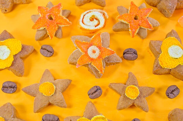 Weihnachtszuckerplätzchen in Form eines Sterns mit kandierter Fruchtkaffee-Orangenschale auf gelbem Hintergrund