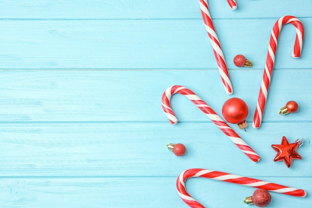Weihnachtszuckerstangen und -dekor auf farbigem hölzernem Hintergrund