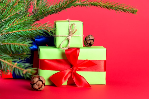 Weihnachtszusammensetzung. Grüne Geschenkboxen unter dem Weihnachtsbaum auf einem Rot. ein Weihnachtsgeschenk