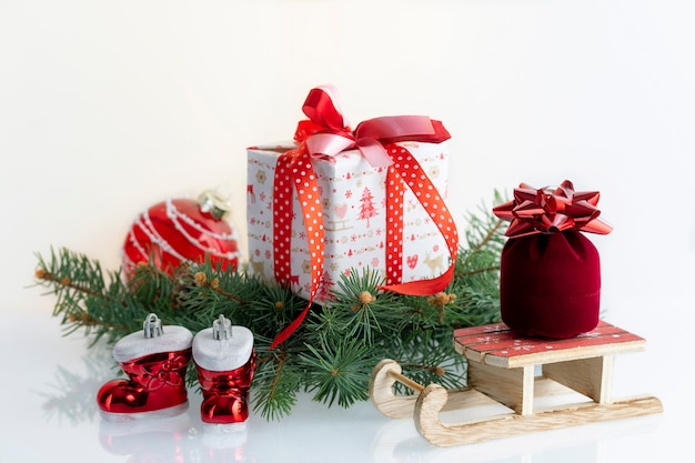 Weihnachtszusammensetzung mit Dekorationen, Geschenkboxen, Flitter, Stiefeln und Pferdeschlitten von Santa Claus auf Weiß