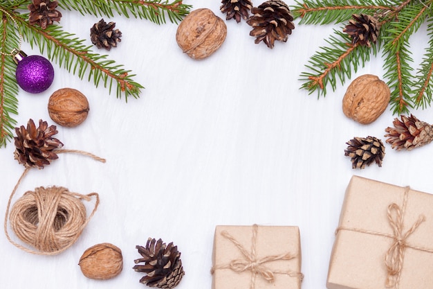 Weihnachtszusammensetzung. Tannenzweige, Geschenke, Tannenzapfen, Walnüsse auf weißem Tabellenhintergrund