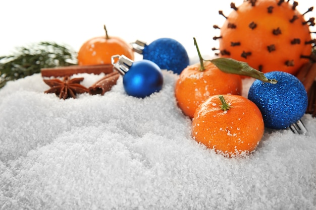 Weihnachtszusammensetzung von Zitrusfrüchten, Gewürzen und Schnee auf weißem Hintergrund, Nahaufnahme