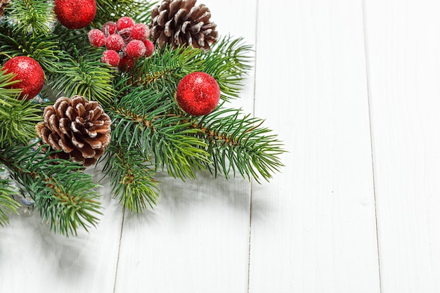 Weihnachtszusammensetzung Weihnachtsbaumast mit Spielzeugkegeln auf einem hölzernen Hintergrund