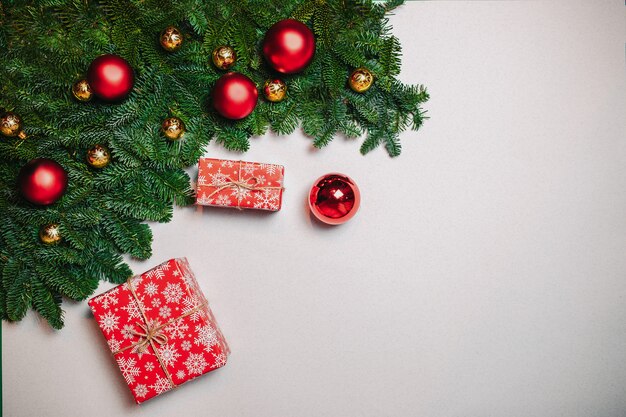 Weihnachtszusammensetzung. Weihnachtsgeschenk, Tannenzweige auf weißem Hintergrund. Flache Lage, Draufsicht, Kopienraum. Rote Weihnachtskugeln und Zuckerstangen.