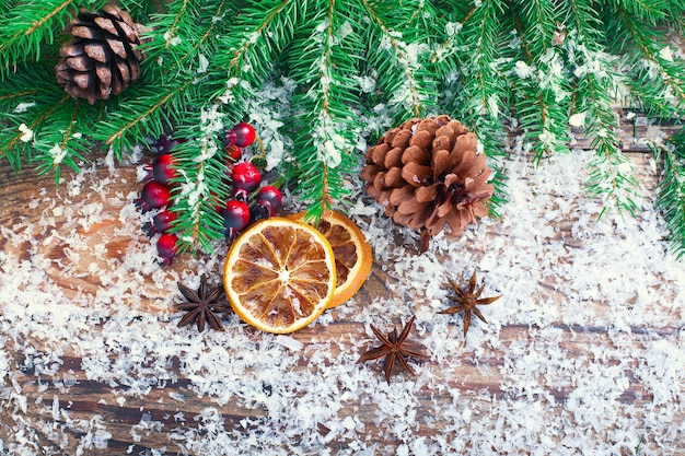 Weihnachtszweig und Zapfen, Zimt, getrocknete Orange auf Vintage-Schreibtisch