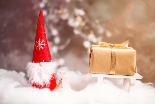 Weihnachtszwerg-Grußkarte mit Bokeh-Lichterketten und Schnee, Wintersaison, Geschenk auf dem Schlitten