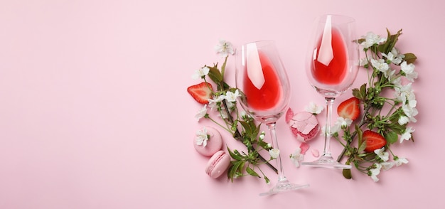 Wein, Makronen, Erdbeeren und Blumen auf rosa Hintergrund