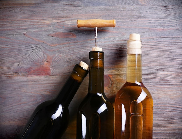 Wein mit drei Flaschen und Korkenzieher auf hölzernem Hintergrund