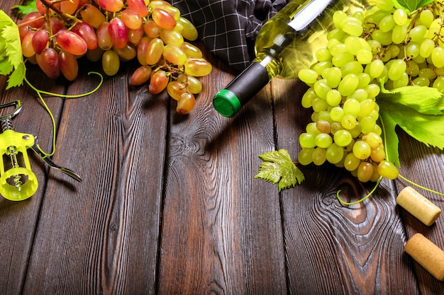 Wein mit Zweigen der weißen Trauben. Auf einem Holztisch.