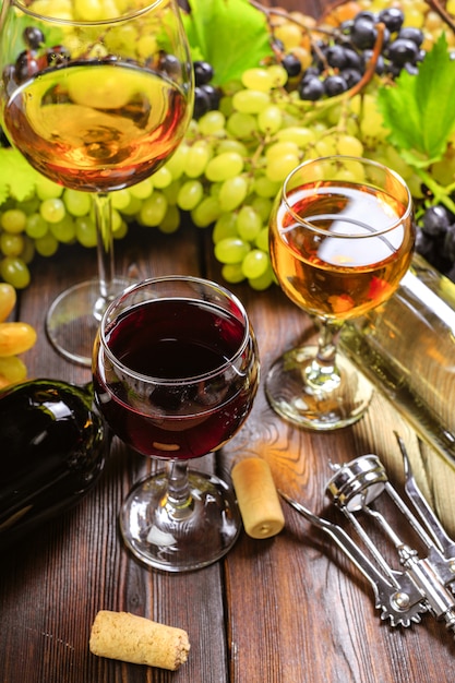 Wein mit Zweigen der weißen Trauben. Auf einem Holztisch.