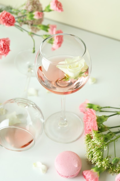 Wein, süße Speisen und Blumen auf weißem Tisch