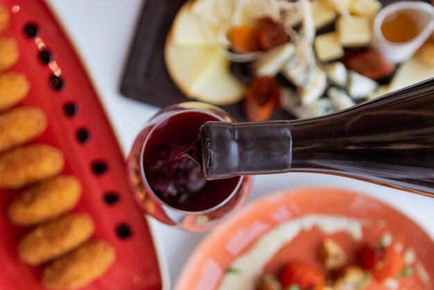 Wein wird aus einer Flasche in ein Glas gegossen vor dem Hintergrund eines Tisches mit Essen