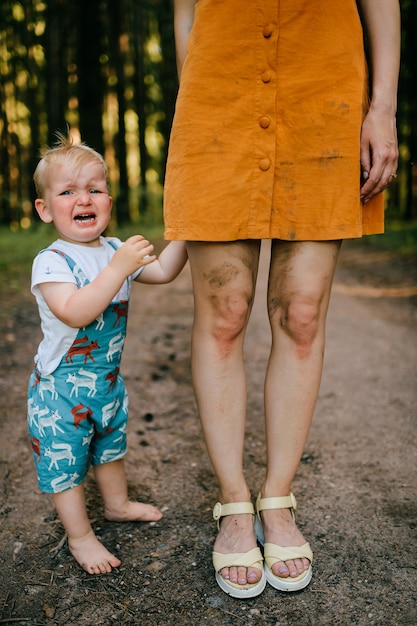 Weinender kleiner Junge, der mit Mamas Beinen aufwirft