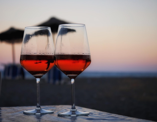 Weingläser auf dem Tisch am Strand gegen den Himmel bei Sonnenuntergang