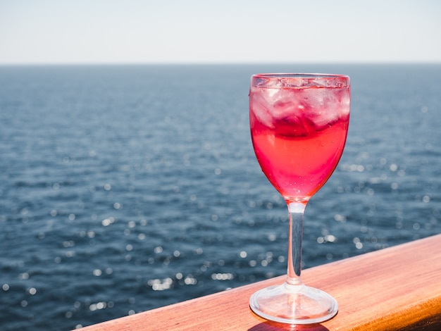 Weinglas mit rosa Cocktail- und Eiswürfeln
