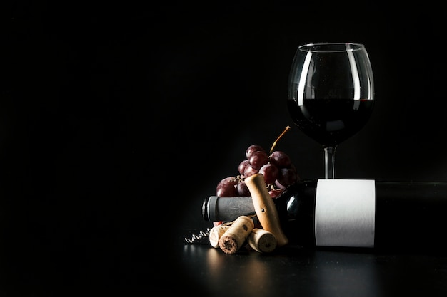 Weinglas und Flasche nahe Korkenzieher und Traube