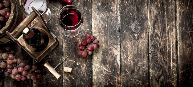 Weinhintergrund Rotwein mit Gläsern mit Trauben auf einem hölzernen Hintergrund