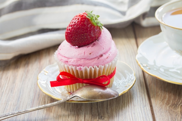 Weinlese-Cupcake mit frischer Erdbeere im Teller auf Holztisch