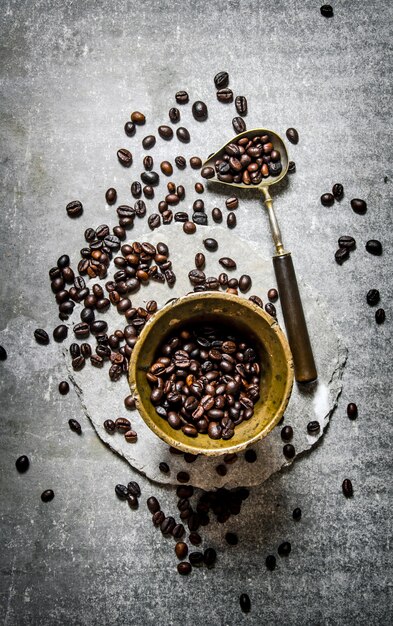 Weinlese gerösteter Kaffee in einem Mörser mit Stößel auf grauem Stein.