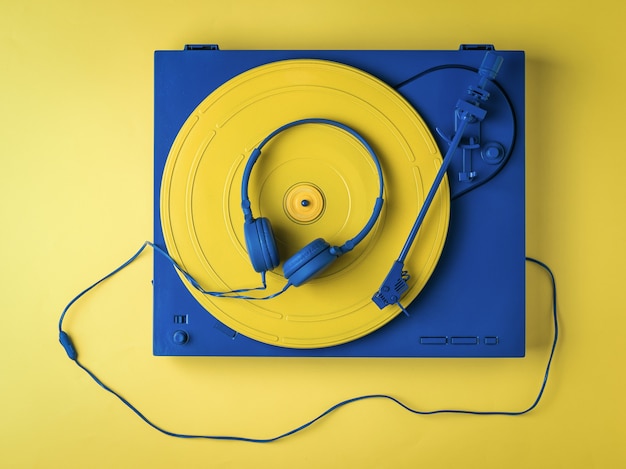 Foto weinlese-vinyl-plattenspieler und blaue kopfhörer auf gelbem hintergrund. retro musikausrüstung.