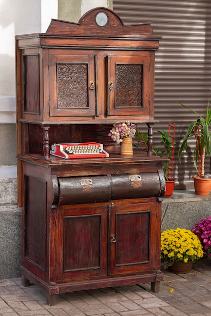 Weinleseholzschrank mit alter Schreibmaschine und Blumen im Freien