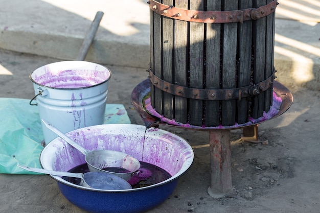 Weinpresse mit rotem Most und Schraubenschnecke Winzerhände hautnah