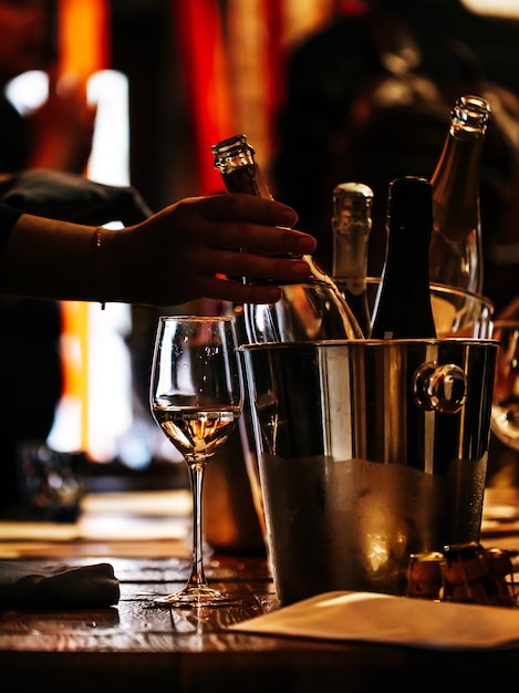 Weinprobe: Auf einem Holztisch steht ein Glas Wein, und ein silberner Eimer zum Abkühlen der Weine