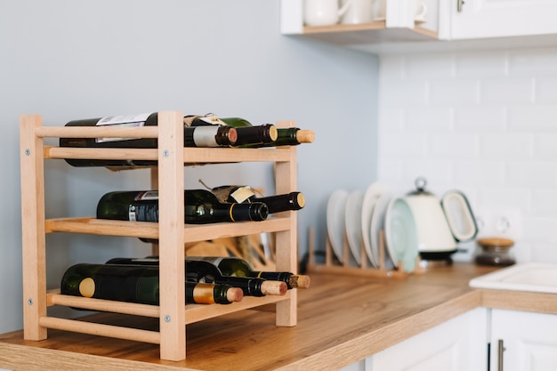 Weinregale aus Holz mit Flaschen auf dem Tisch in der modernen Küche.