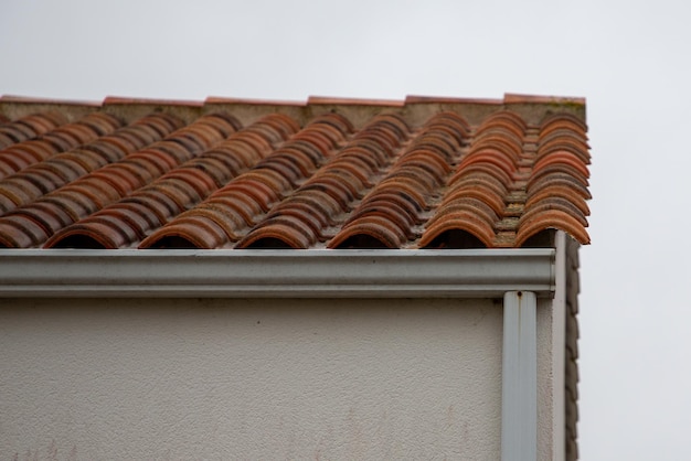 Weiß-beige Dachrinne auf dem Dach des Gebäudes und Fallrohr an der Wand