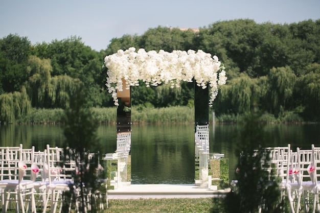 Foto weiß gespiegelter hochzeitsbogen verziert mit weißen blumen