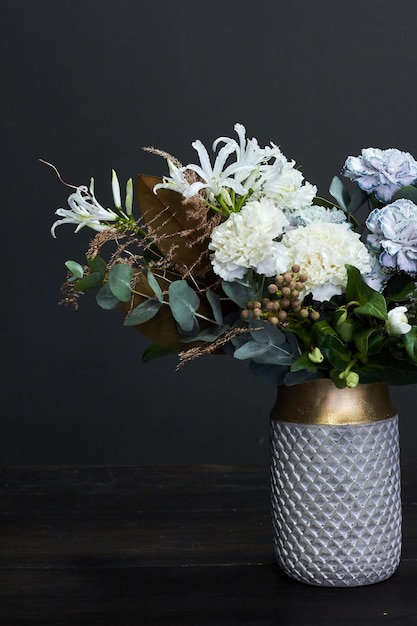 Weiß getönten Blumenstrauß im Vintage-Stil in einer Vase aus Keramik auf dunkel