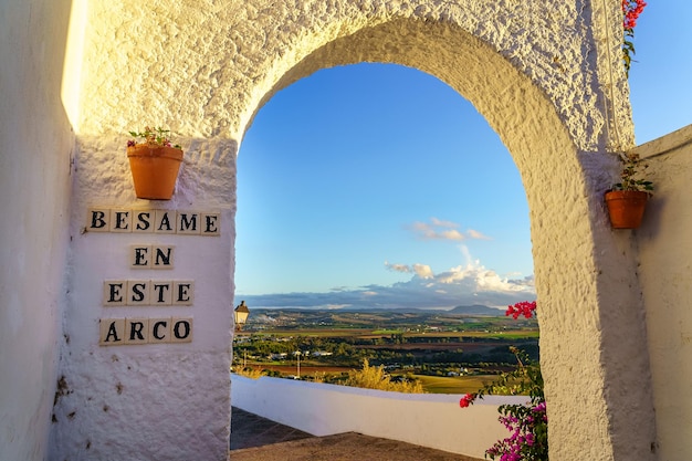 Weiß getünchter Wandbogen in einem alten Dorf Andalusiens mit einem Schild für Paare zum Küssen