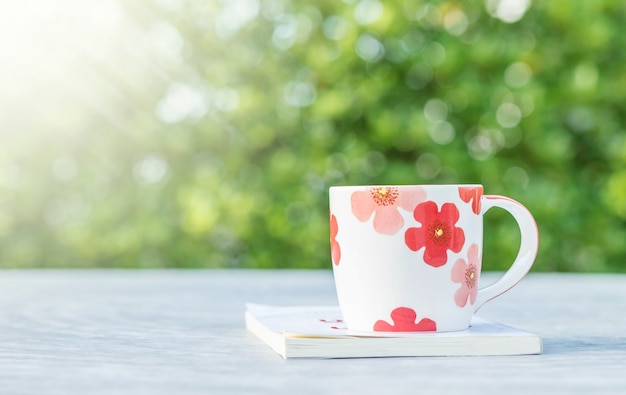 Weißbuch des netten Tasse Kaffees der Nahaufnahme auf unscharfem konkretem strukturiertem Hintergrund der Schreibtisch- und Gartenansicht morgens