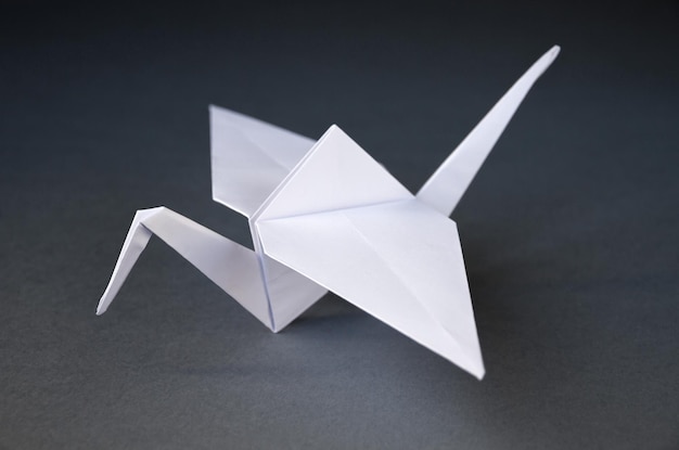 Weißbuch-Kran-Origami isoliert auf grauem Hintergrund