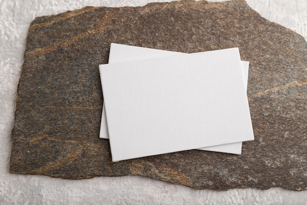 Foto weißbuch visitenkartenmodell mit stein auf grauem betonhintergrund flach liegend leinwand kopierraum