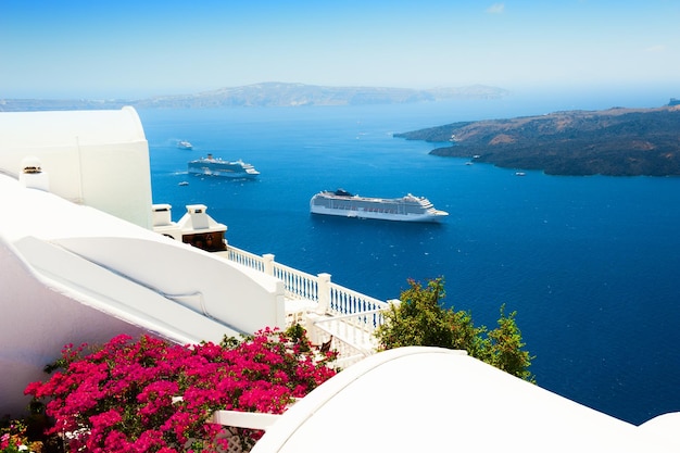 Weiße Architektur auf der Insel Santorini, Griechenland. Blumen auf der Terrasse mit Meerblick. Reiseziele Konzept
