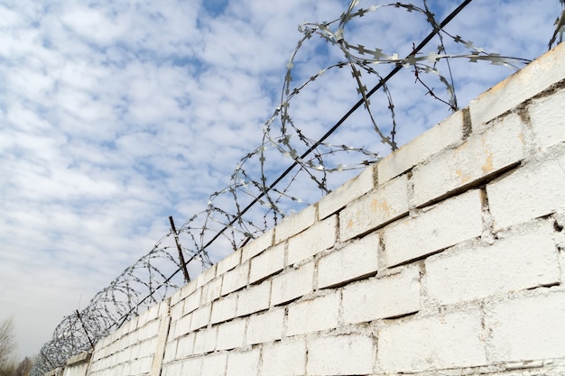 Weiße Backsteinmauer und Stacheldraht