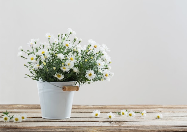 Weiße Blumen auf Eimer auf Holztisch