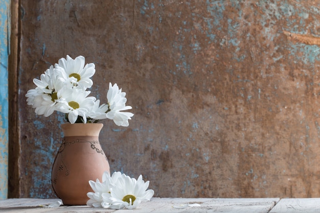 Weiße Blumen im Krug auf alter gemalter Holzoberfläche