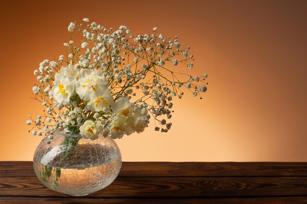 Weiße Blumen in Glasvase auf Holztisch