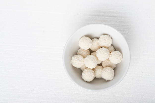 Weiße Bonbons mit Kokosnuss, Nüssen und Sahne in einem Teller auf weißem Hintergrund