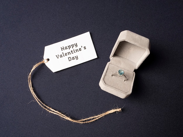 Foto weiße box, in der sich ein ring mit einem blauen stein befindet und daneben eine weiße note