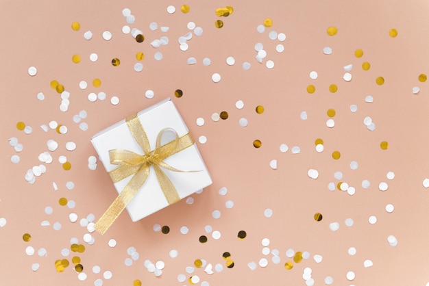 weiße Box mit Band Weihnachtsgeschenk mit Konfetti flach auf beige Hintergrund legen