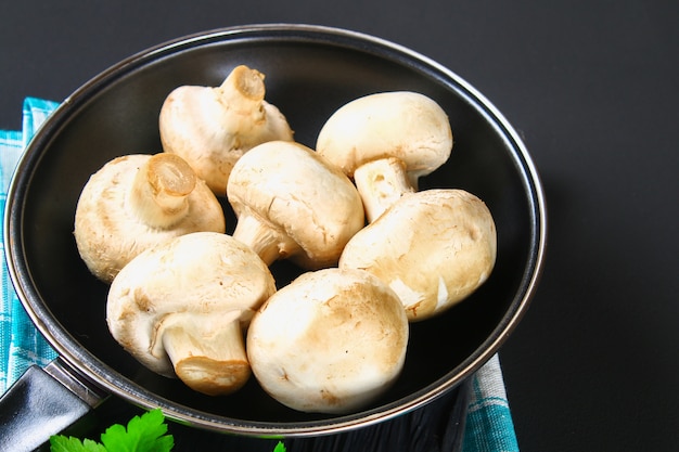 Weiße Champignons mit Petersilie auf einer grauen dunklen Tabelle. Pilze.