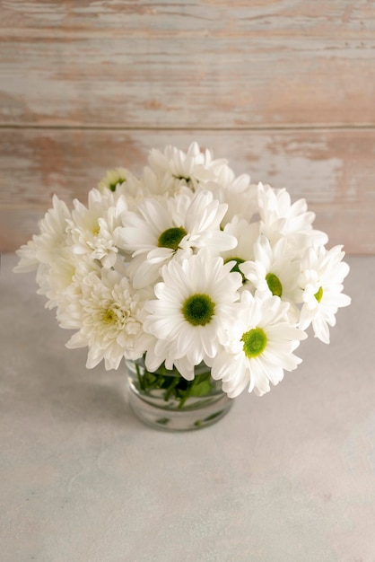 Weiße Chrysantheme Blumenstrauß in Vase Frühlingskomposition mit Gänseblümchen Abstrakter rustikaler Hintergrund
